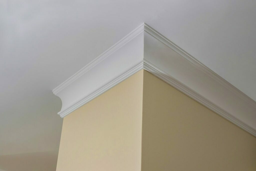 White PVC crown moulding outlines the top of a cream colored wall